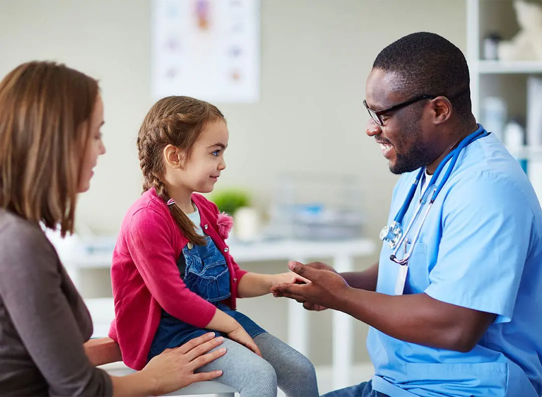 young girl with her mother as a smiling doctor performs a checkup on the girl