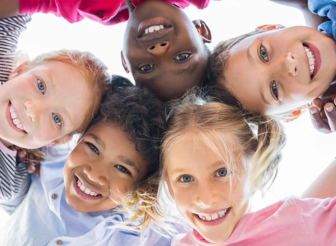 circle of smiling children looking down toward the camera